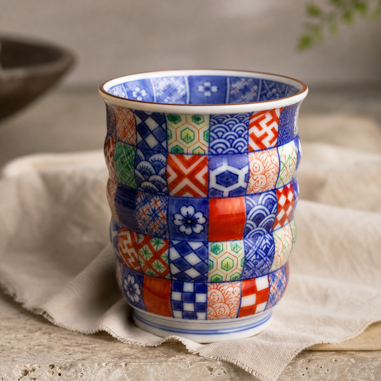 Luxury ecommerce image of a multicolor Kyoto ware inspired yunomi cup with hand-painted komon motifs