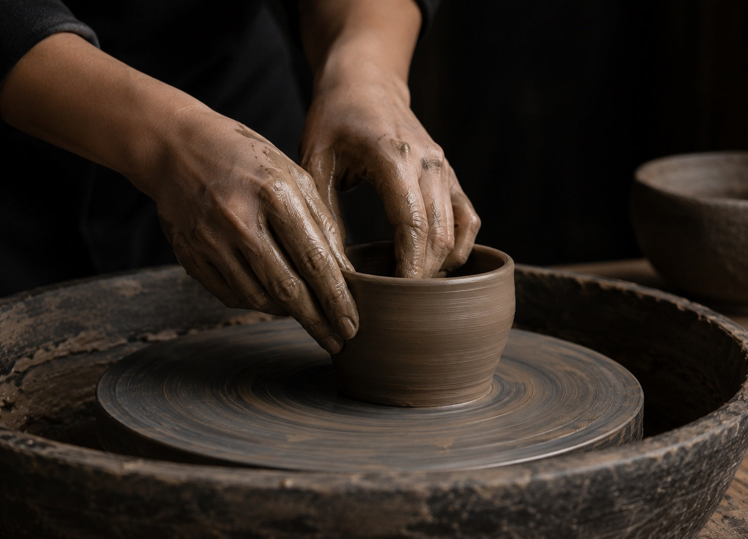 Hands shaping a Japanese ceramic vessel on a wheel