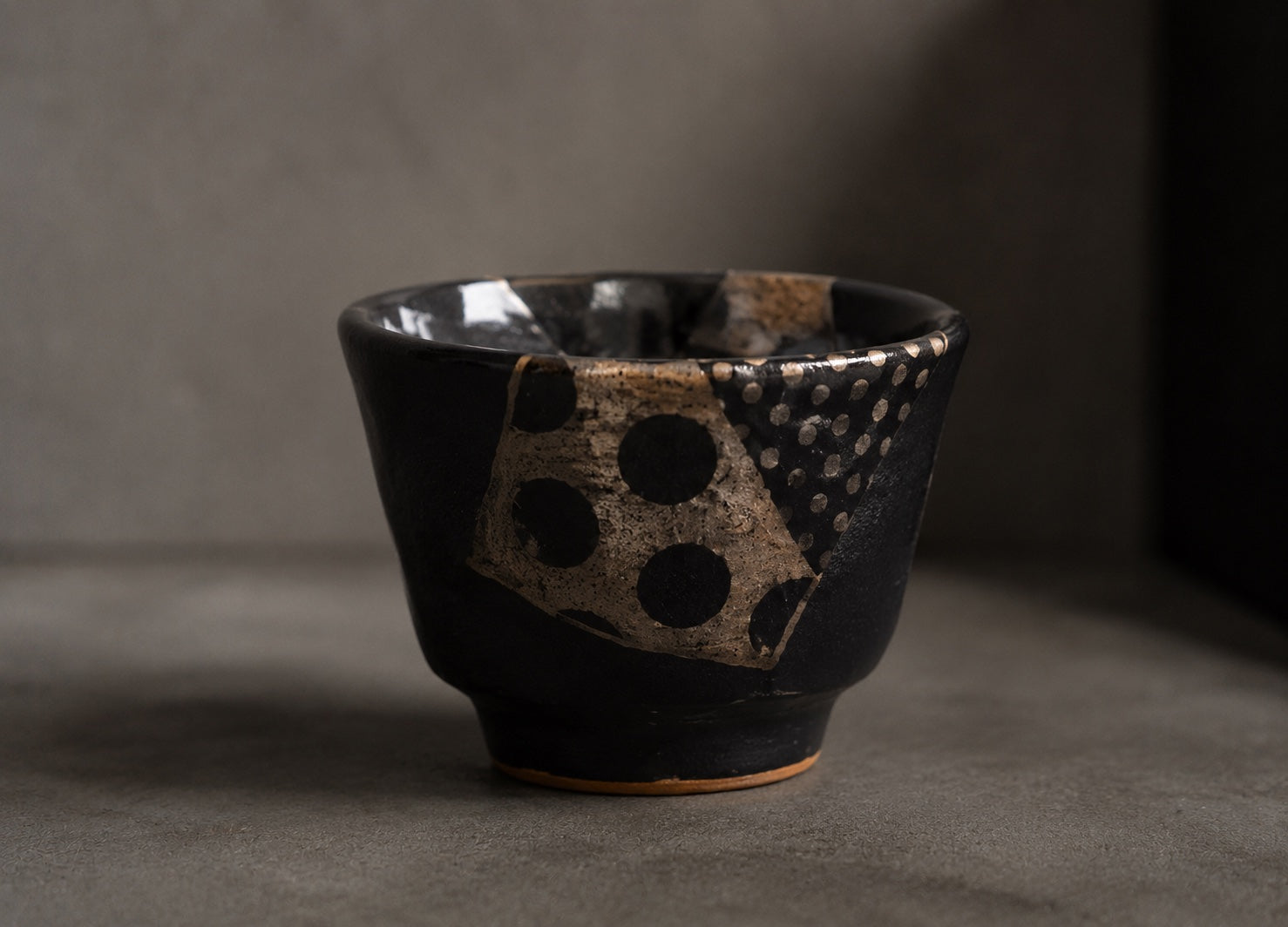 Close view of a dark Japanese cup with expressive repaired surface details